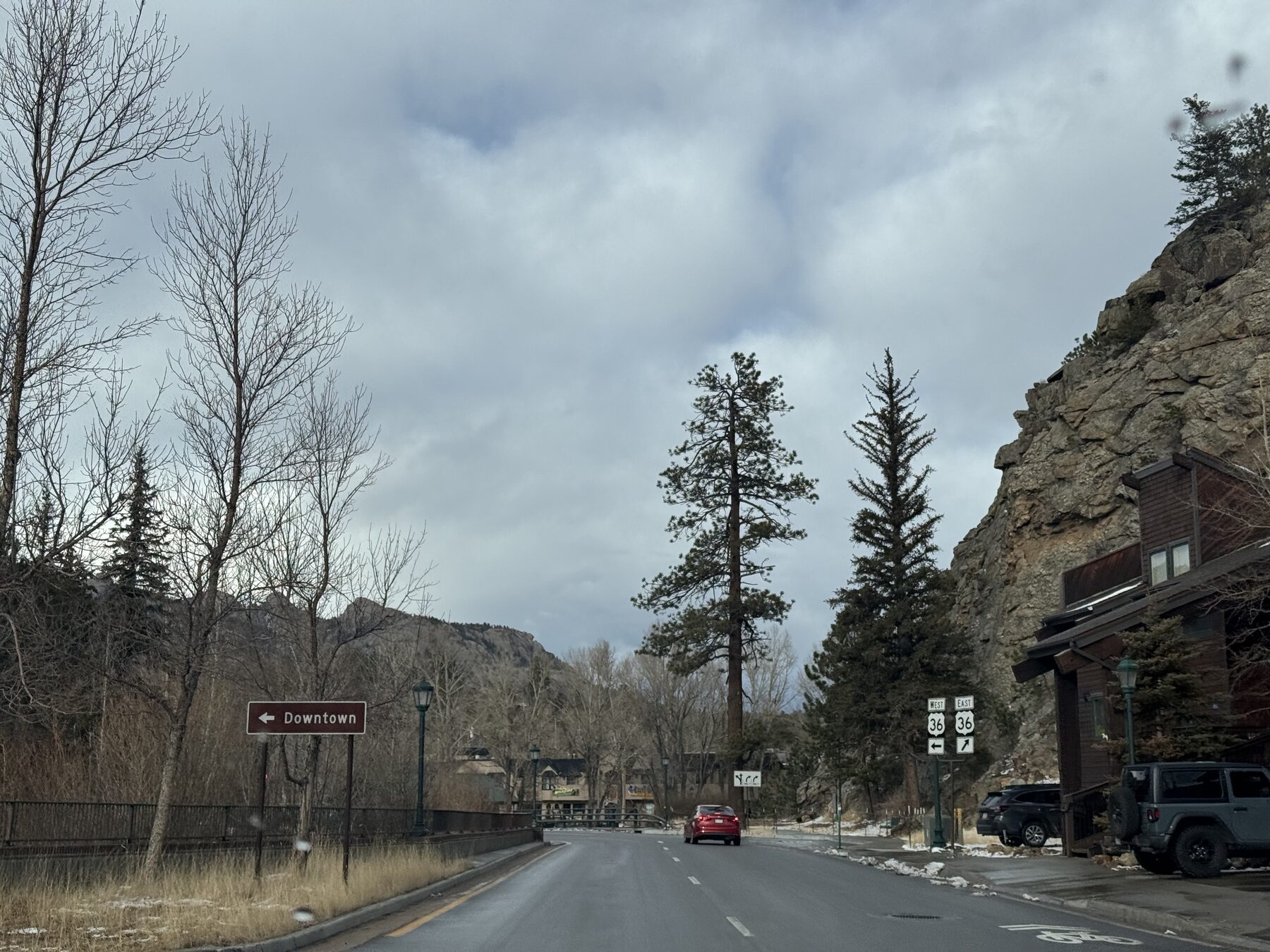 The road into downtown Estes Park, lined with pines and rock outcrops under a moody sky