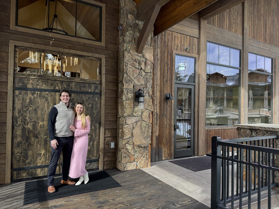 Joshua and Hailey standing together at the timber-and-stone entrance of the venue during a site visit